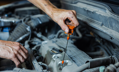 A man is checking the engine oil on a car for a replacement. Close-up. Selective focus.