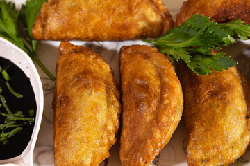six fried cireng arranged neatly on a plain white base and decorated with celery leaves in close up