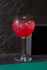 Berry lemonade elegantly presented in a wine glass against a stark black background. Minimalist design, ideal for a bar card