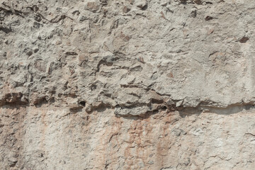 Plastered stone surface with rocks. Grunge texture background. An old weathered wall.