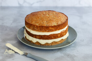 Cream cheese icing being spread on a three tier baked hummingbird cake