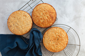 Baked cakes on wire cooling racks after coming out of the oven with a navy dish towel