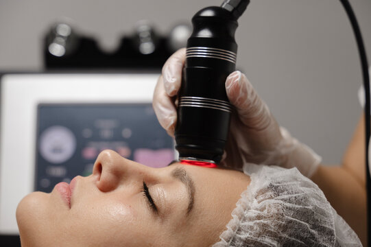 Dermatologist doing Rf lifting procedure on woman's face in clinic