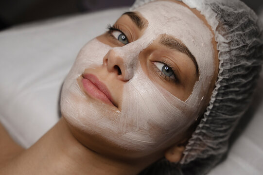 Smiling woman with skincare face mask in beauty salon
