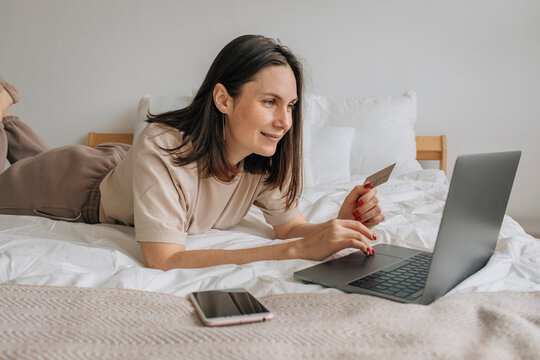 Happy Woman Using Credit Card For Shopping On Laptop At Home