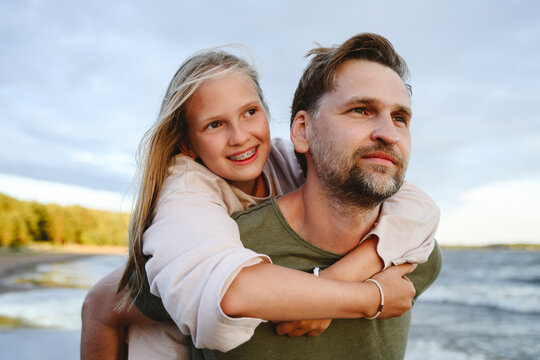 Smiling father giving piggyback ride to daughter at beach