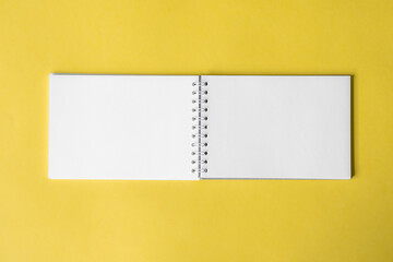 Opened notepad on a yellow background. Composition of writing to-dos for the day. The notebook lies on a plain background with space for writing. 