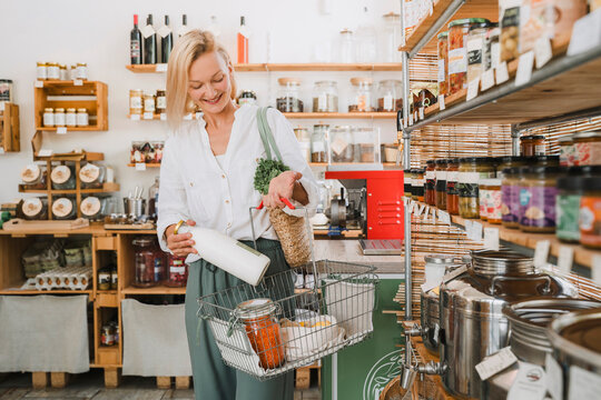Happy blond woman with basket shopping at zero waste store