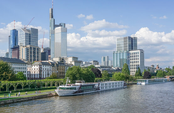 Germany, Hesse, Frankfurt, ship moored along river with downtown skyscrapers in background