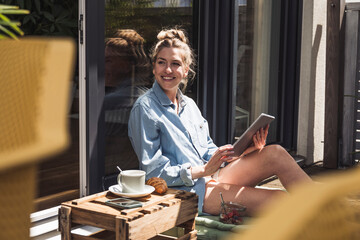 Woman relaxing on balcony with digital tablet in hands