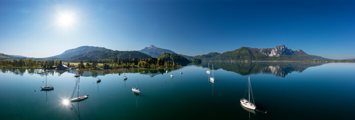 Austria, Upper Austria, Loibichl, Drone panorama of sailboats in Mondsee lake with Schafberg and Drachenwand mountains in background