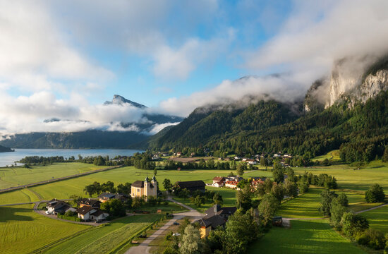 Austria, Upper Austria, Sankt Lorenz, Drone view of fog gathering over small village with mountains in background