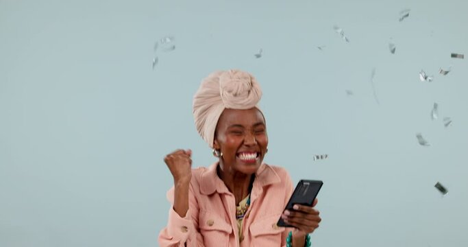 Excited black woman, phone and celebration with confetti in winning or promotion against a studio background. Happy African female person reading good news or discount in success on mobile smartphone