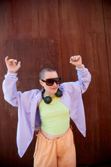 Vertical portrait of badass bald young woman dancing outdoors against rust metal wall