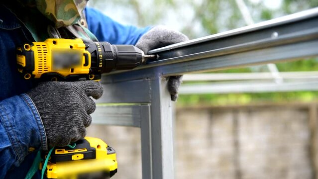 Worker installing screw the Channel Wire Lock to greenhouse 