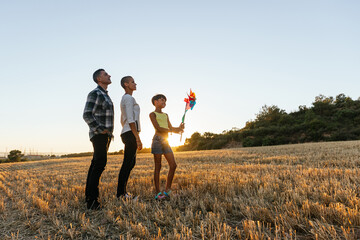 Mom, dad and daughter having fun in the field at sunset.