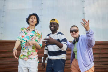 Waist up portrait of diverse group of young people dancing hip-hop outdoors in city wearing trendy outfits and looking at camera