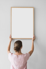 Woman holding blank wooden picture frame mockup on white wall, Artwork mock-up in minimal interior...