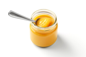 Jar of orange puree for babies or children with a spoon inside isolated on white...
