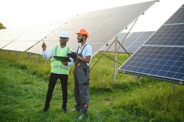 A team of multiracial workers in a field of solar panels.