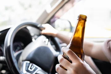 Foto op Plexiglas Intoxicated woman driver holding bottle of beer,asian female drinking alcohol while driving motor vehicle,risk or danger of road accidents,Campaign against drunk driving,Don't drink and drive concept © Satjawat