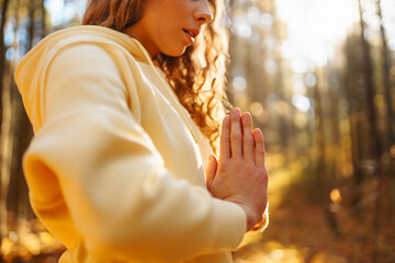 An active woman in sportswear performs yoga exercises in the autumn forest on fallen leaves,...