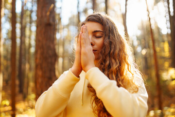 An active woman in sportswear performs yoga exercises in the autumn forest on fallen leaves,...
