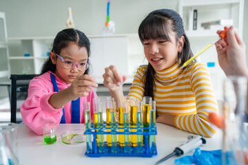 Group of young asian schoolgirls learning research and doing experiment in chemistry classroom. Fun...