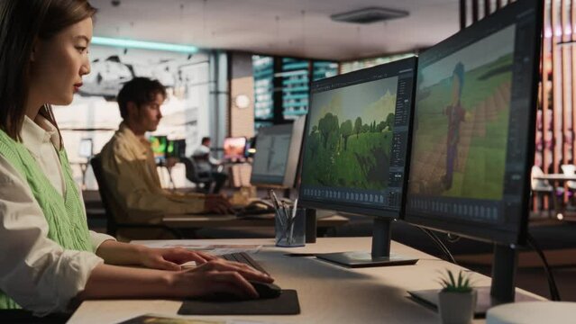Asian Woman Using Desktop Computer And Designing In 3D modelling Software Unique World And Characters For Survival Video Game In Diverse Office. Female Game Developer Creating Immersive Gameplay.