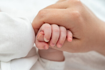 Newborn's delicate grip on mother's thumb exudes trust. Concept of pure maternal connection