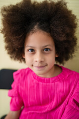 Smiling cute little african american girl with two pony tails looking at camera. Portrait of happy...