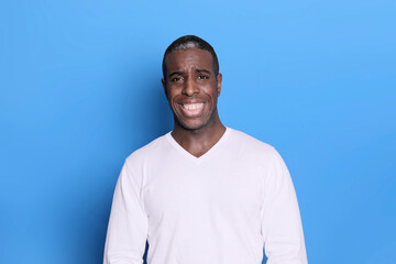 Portrait of cheerful young african-american guy wearing white casual sweater posing isolated on...