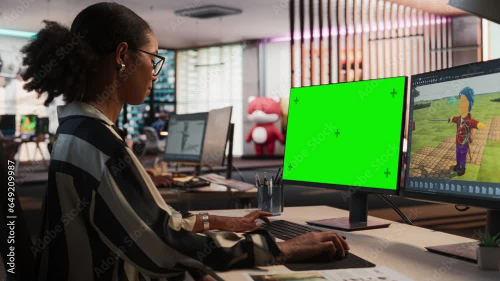 Fototapete Female Black Game Designer Using Desktop Computer With Green Screen Chromakey on Display, Designing Characters In 3D modelling Software For RPG Video Game. Woman Working In Game Development Office