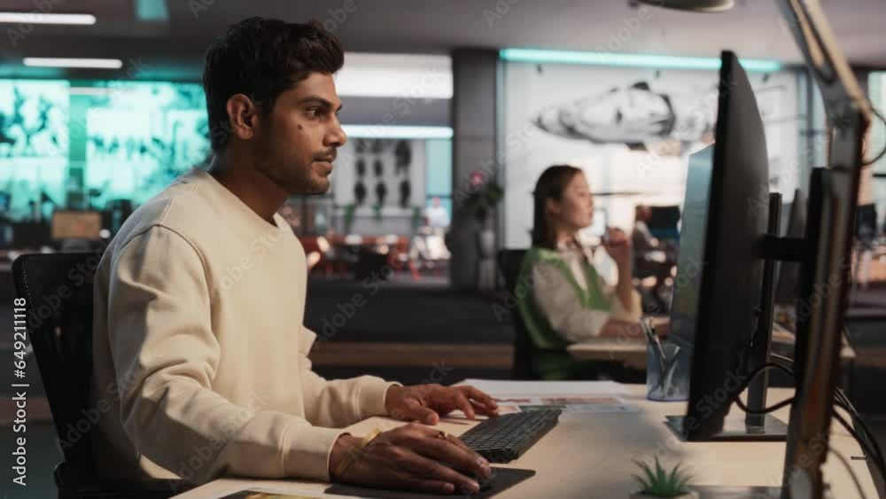 Poster Indian Male Game Developer Using Desktop Computer With 3D modelling Software To Design Characters And World For Immersive Survival Video Game. Man Working In Game Design Company Diverse Office.