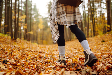 Autumn mood. Close-up of female legs in hiking boots on autumn leaves in the park. The concept of...