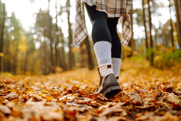 Autumn mood. Close-up of female legs in hiking boots on autumn leaves in the park. The concept of...
