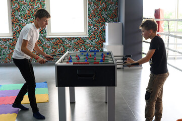 Active recreation in the game room, children play table football.