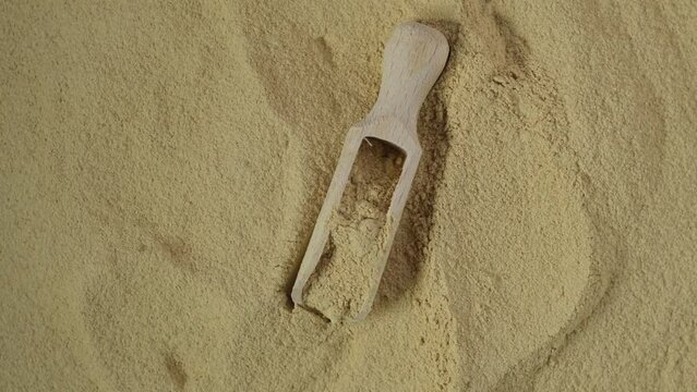 Maca powder in wooden scoop, top view. 4K video, Rotating. Maca gelatinized flour, close-up. Peruvian superfood, natural food supplement.