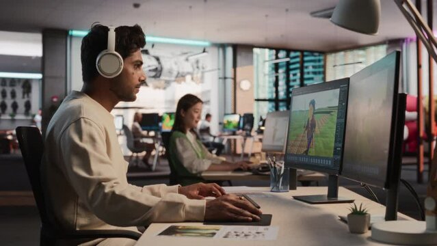 Indian Male Game Developer Using Desktop Computer With 3D modelling Software To Design Characters And World For Immersive Survival Video Game. Man Working In Game Design Studio Diverse Office.