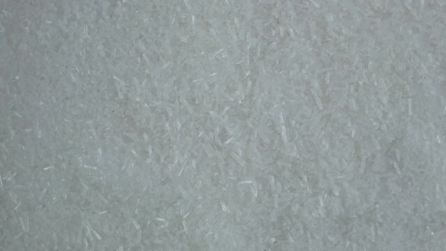 Oblong white crystalline granules ribotide. Mixture of Disodium 5-guanylate E627 and Disodium 5-inosinate E631. Flavor enhancer. I + G. Ribotide powder, close-up. Food additive. 4K Video, Rotating.