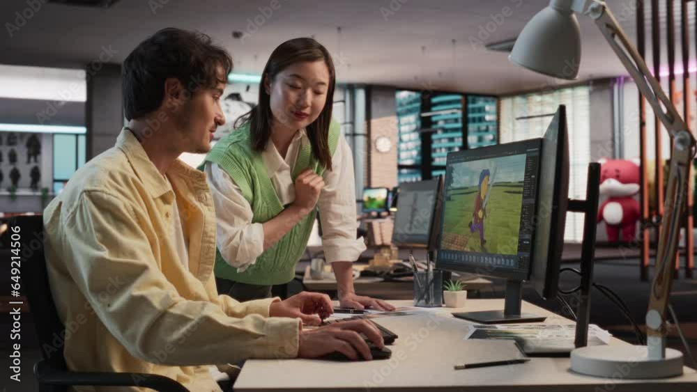 Poster Caucasian Male Game Designer Using Desktop Computer With 3D modelling Software And Talking to Asian Female Project Manager in Game Development Studio Office. Diverse Colleagues Discussing New RPG Game