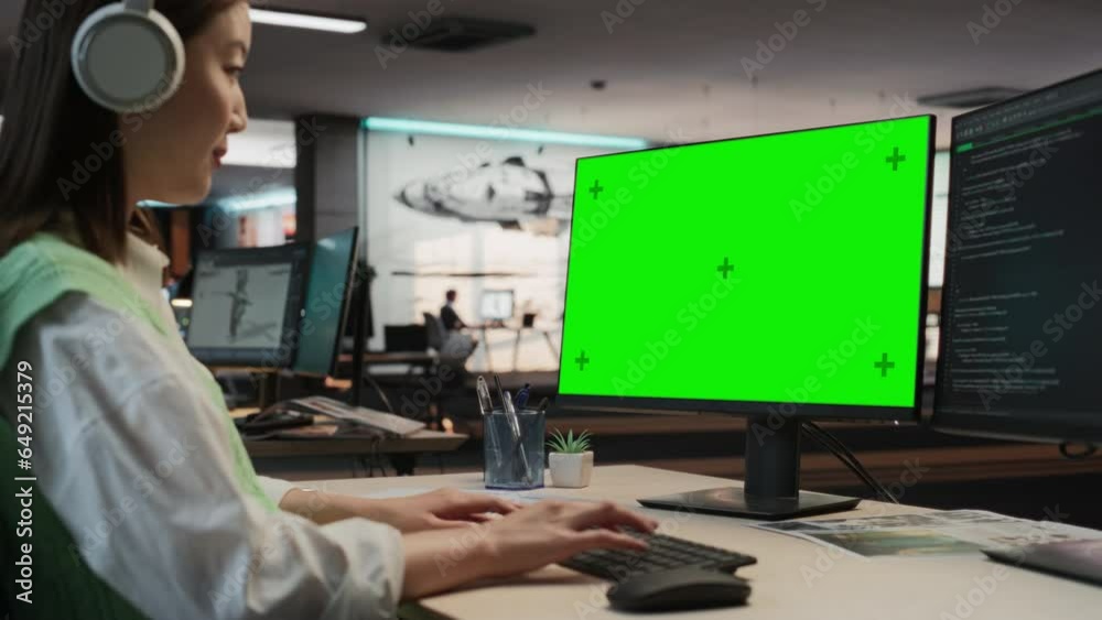Fototapete Female Asian Game Programmer Coding On Desktop Computer With Green Screen Chromakey On Display In Game Development Studio Office. Focused Woman Does Gameplay Engineering For New 3D RPG Video Game.