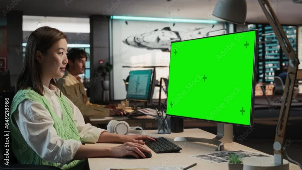 Poster portrait of asian woman sitting at her desk using desktop computer with mock-up green screen chromak