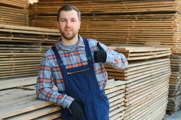 Fototapeta premium Joiner in uniform check boards on timber mill