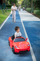 Little boy is riding in a remote controlled car