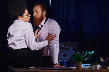 attractive african american woman seducing bearded businessman on work desk in night office, romance
