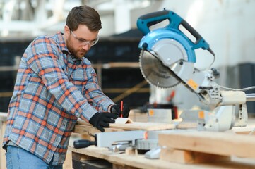 Wood cutting table with electric circular saw. Professional carpenter in uniform cutting wooden board at sawmill carpentry manufacturing . Sawing machine