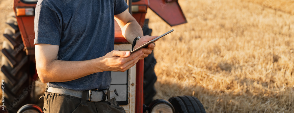 Aufkleber Farmer with a digital tablet is next to an agricultural tractor.