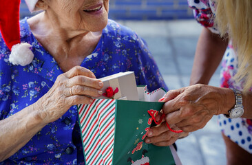 older woman receiving a gift at christmas with affection outside. elderly lifestyle in christmastime