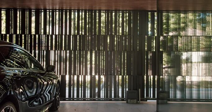 Auto inside modern garage with metal gate at residential house. Black car parked near home